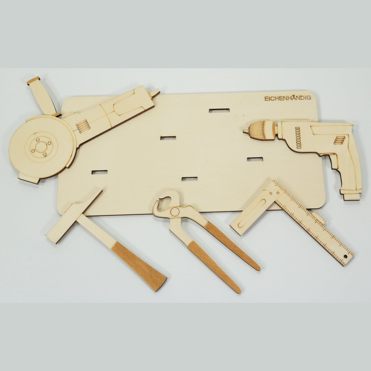 Bausatz des Holz-Werkzeug-Geldgeschenks – einzelne Teile: Trennschleifer, Bohrmaschine, Hammer, Zange und Winkel