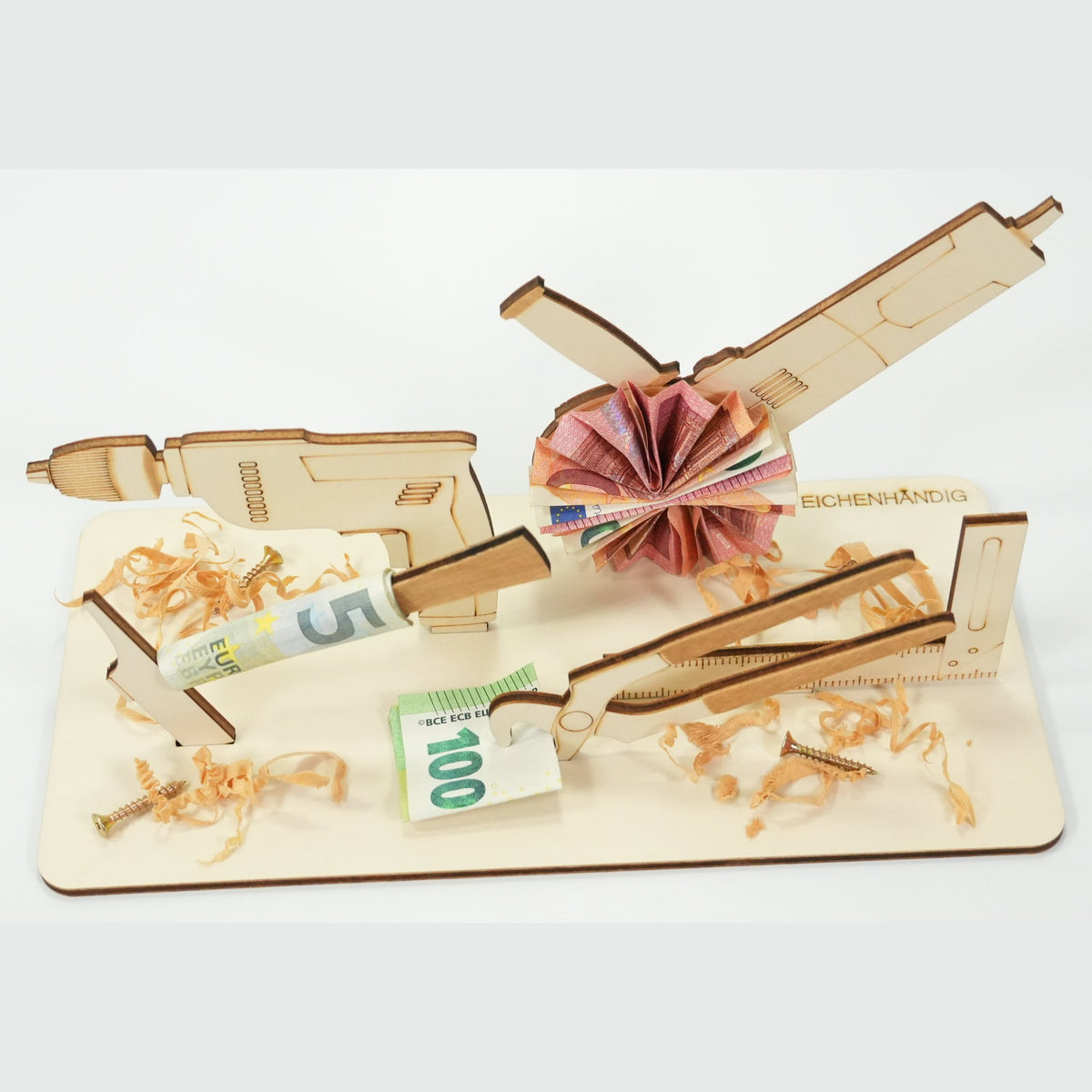 Holz-Werkzeug-Geldgeschenk mit Bohrmaschine, Zange und Trennschleifer, dekoriert mit gefalteten Geldscheinen, Schrauben und Holzspänen
