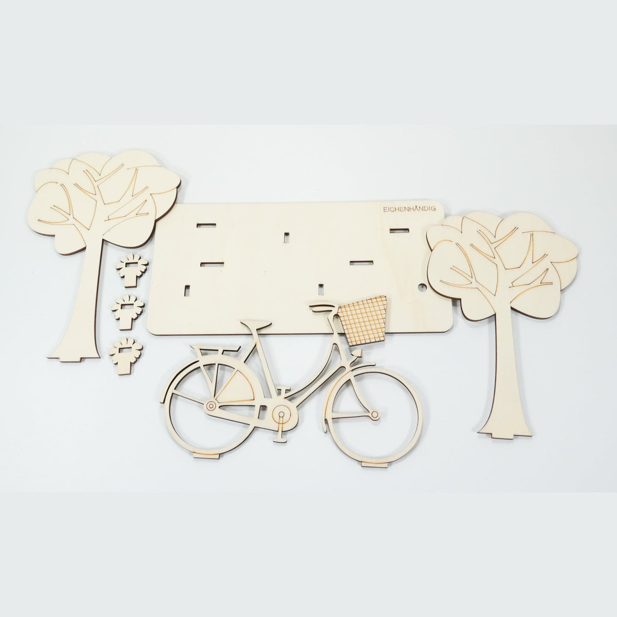Bausatz des Holz-Fahrrads – einzelne lasergeschnittene Teile mit Bäumen, Fahrrad und Blumen