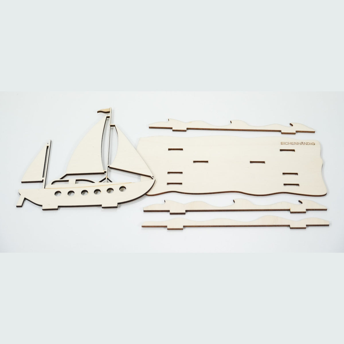 Bausatz des Holz-Segelboots – einzelne Teile mit Boot, Segeln und Wellen zum Zusammenstecken